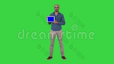 微笑休闲男子呈现一个平板电脑与空白屏幕上的绿色屏幕，铬键。